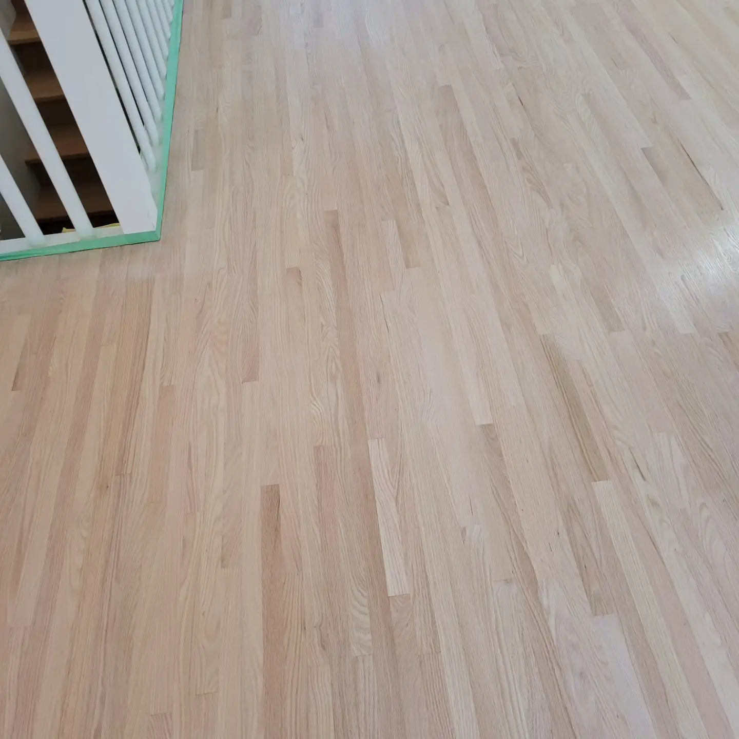 Red oak floor sanded back to bare wood with the railing masked off